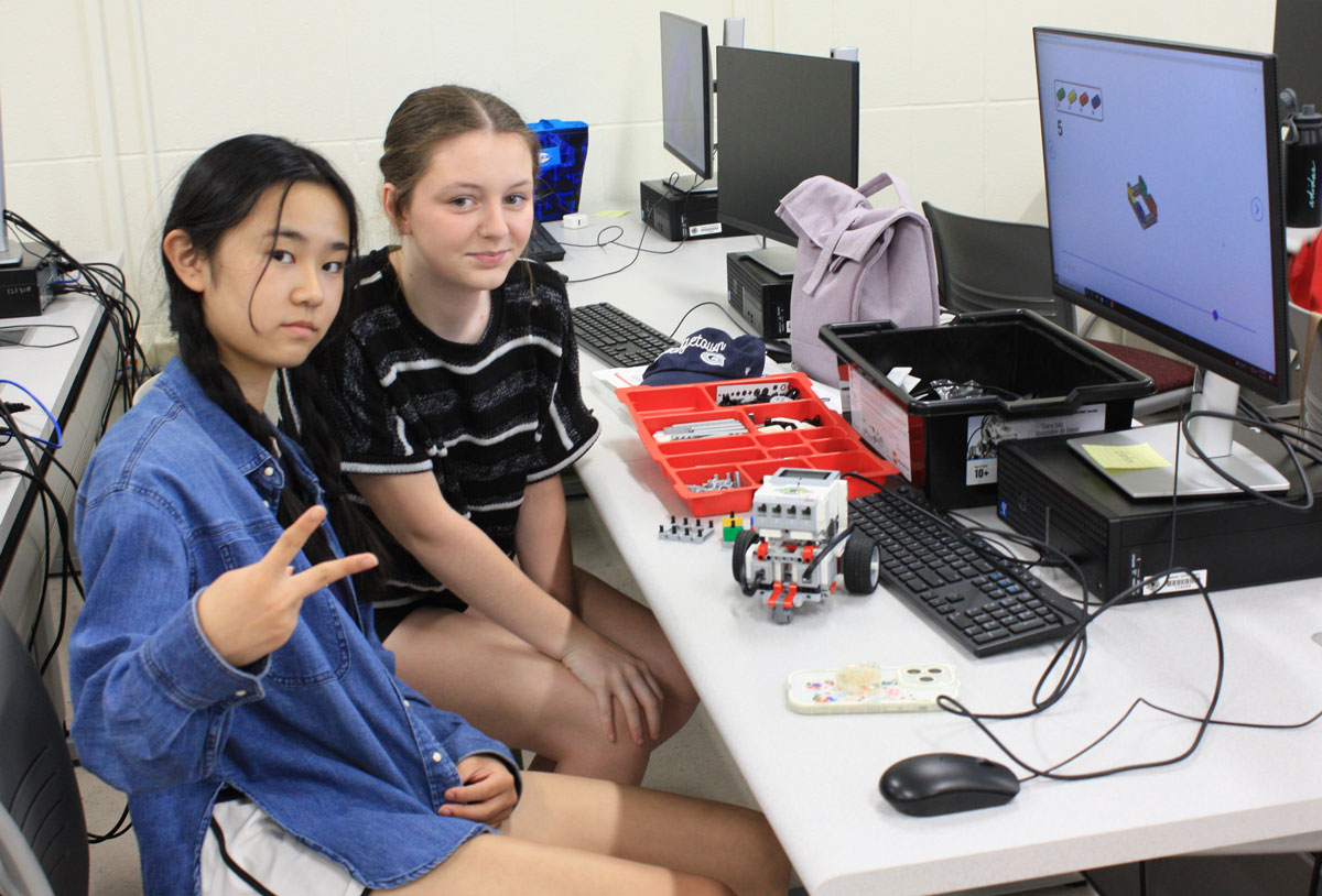 2 students sitting at computer posing for camera