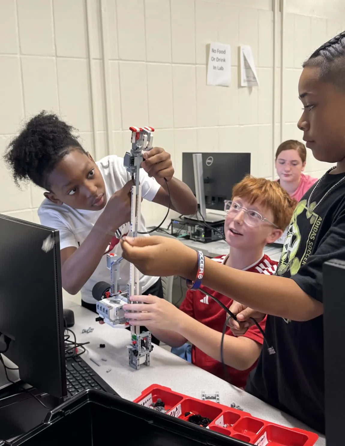 Three students building robot at robotic camp