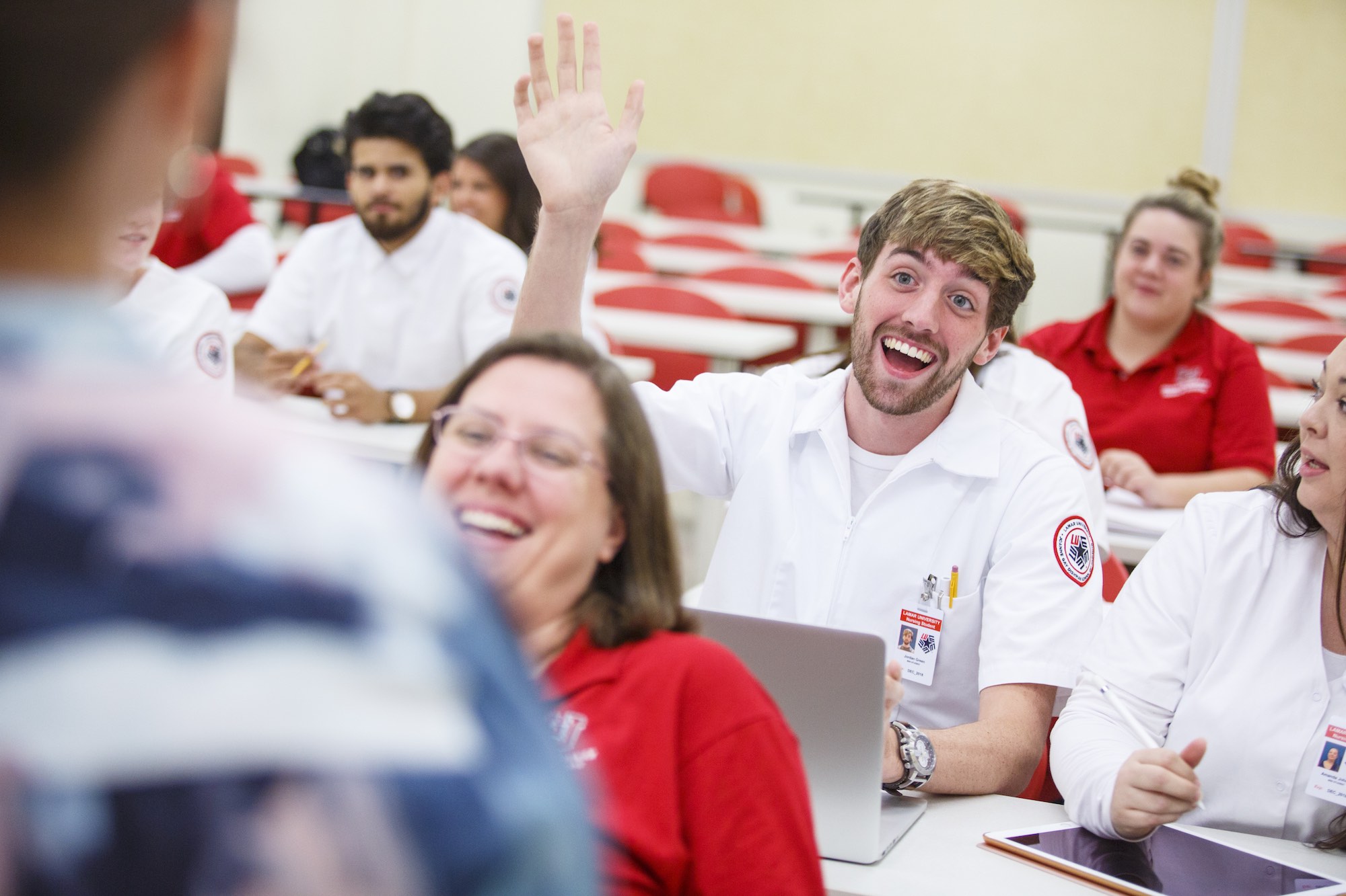 A nursing student in class raises his hand to ask a question.