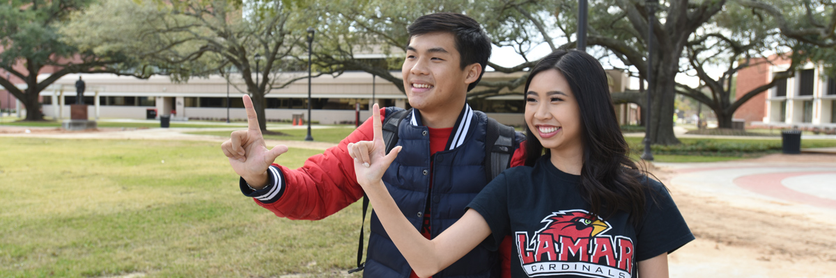Male and female asian students holding up "Lamar" L in the quad.
