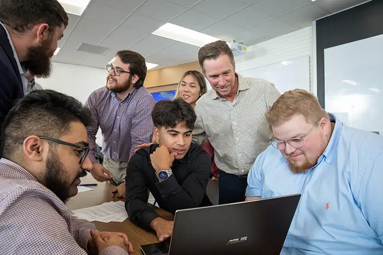 Students look at a laptop during class
