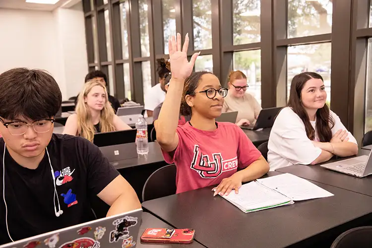 Student raises her hand in a classroom