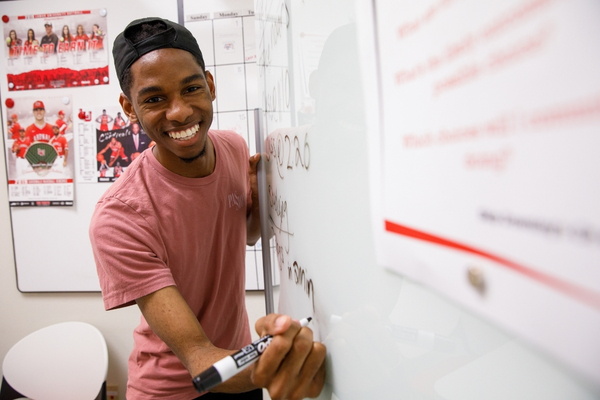 Smiling student writing on board