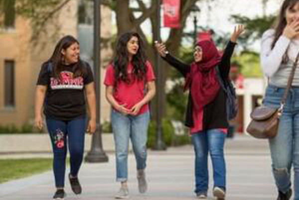 Four students walking three in background one in foreground