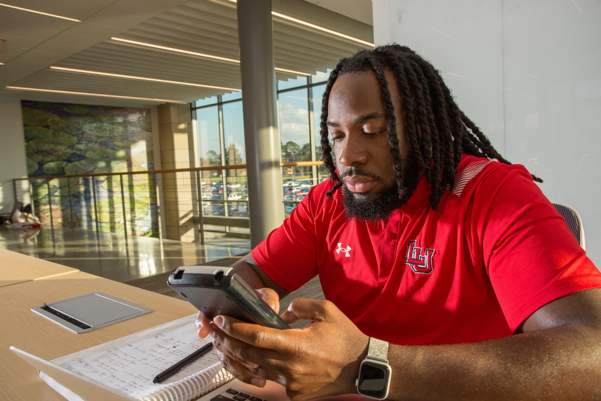 Student in red shirt using calculator