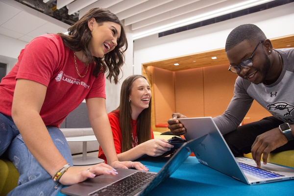 Three students at a table laughing and working together