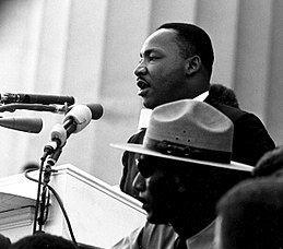 Rev. Dr. Martin Luther King, Jr. speaking behind podium; black and white image