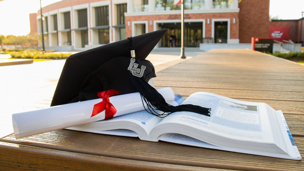 graduation hat and diploma set on top of open text book