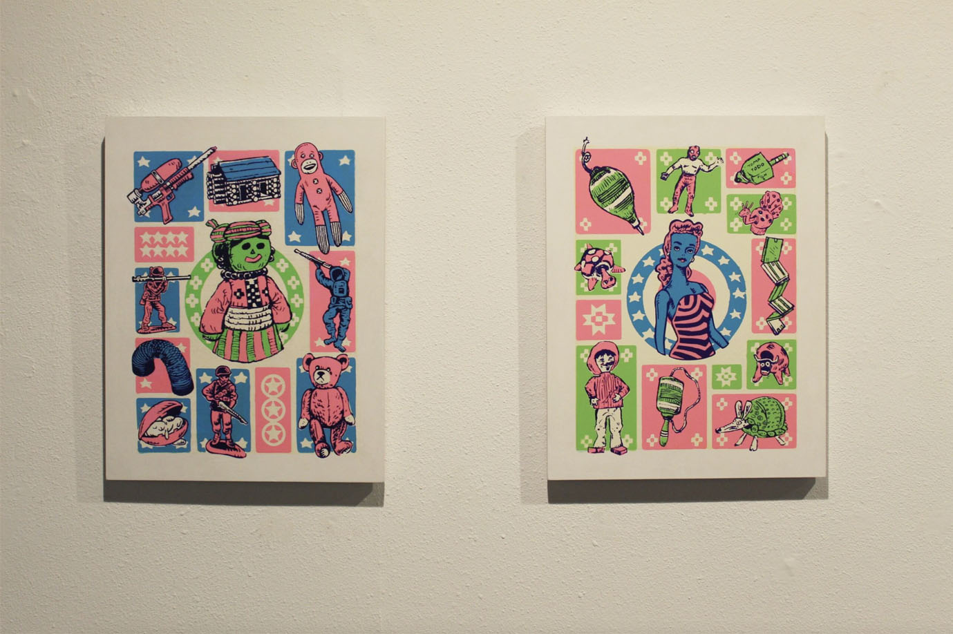 Two canvases featuring colorful collages of playful and whimsical graphics in pink, blue, and green tones mounted on a wall.