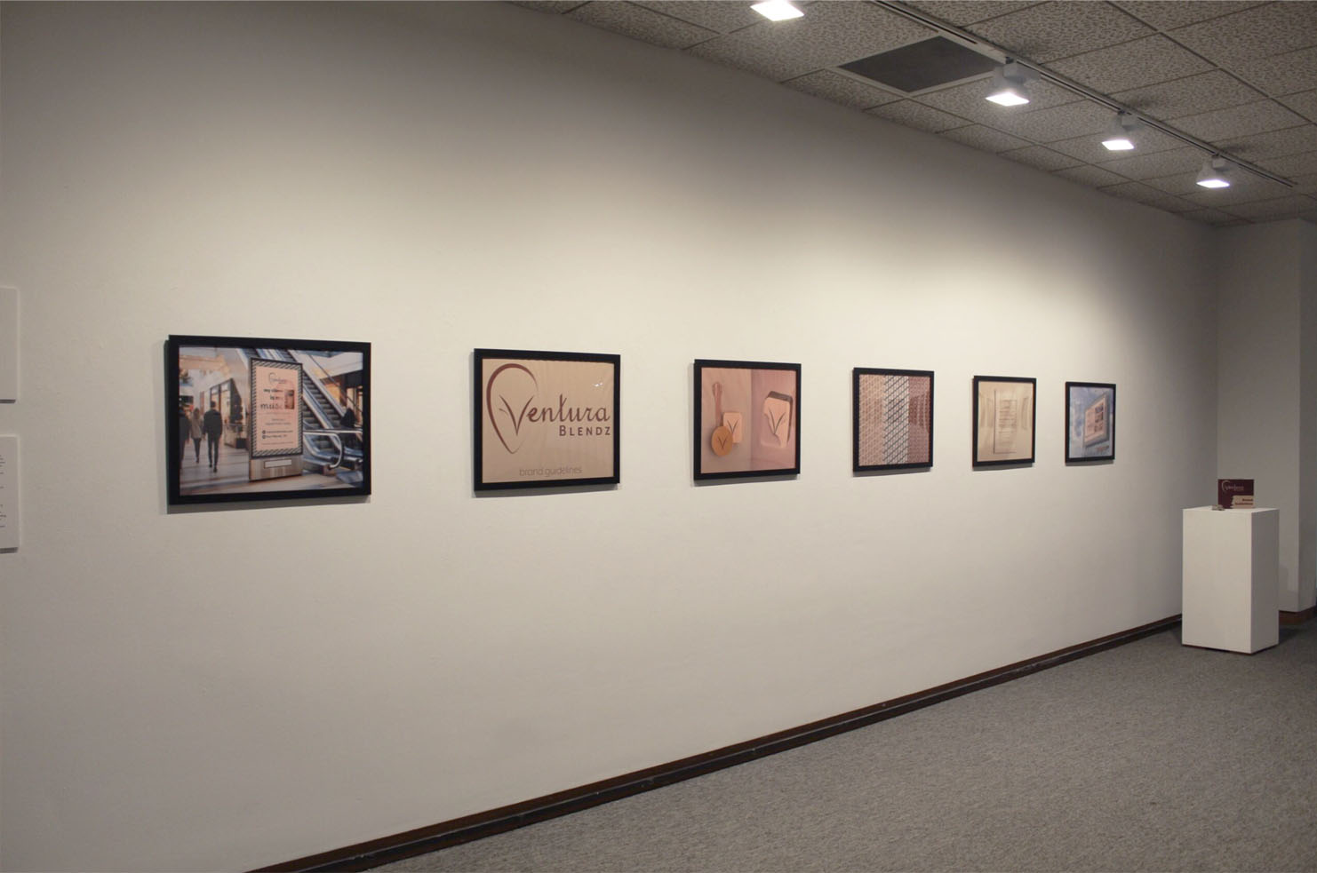 A gallery wall displaying six framed artworks, including a logo and abstract patterns.