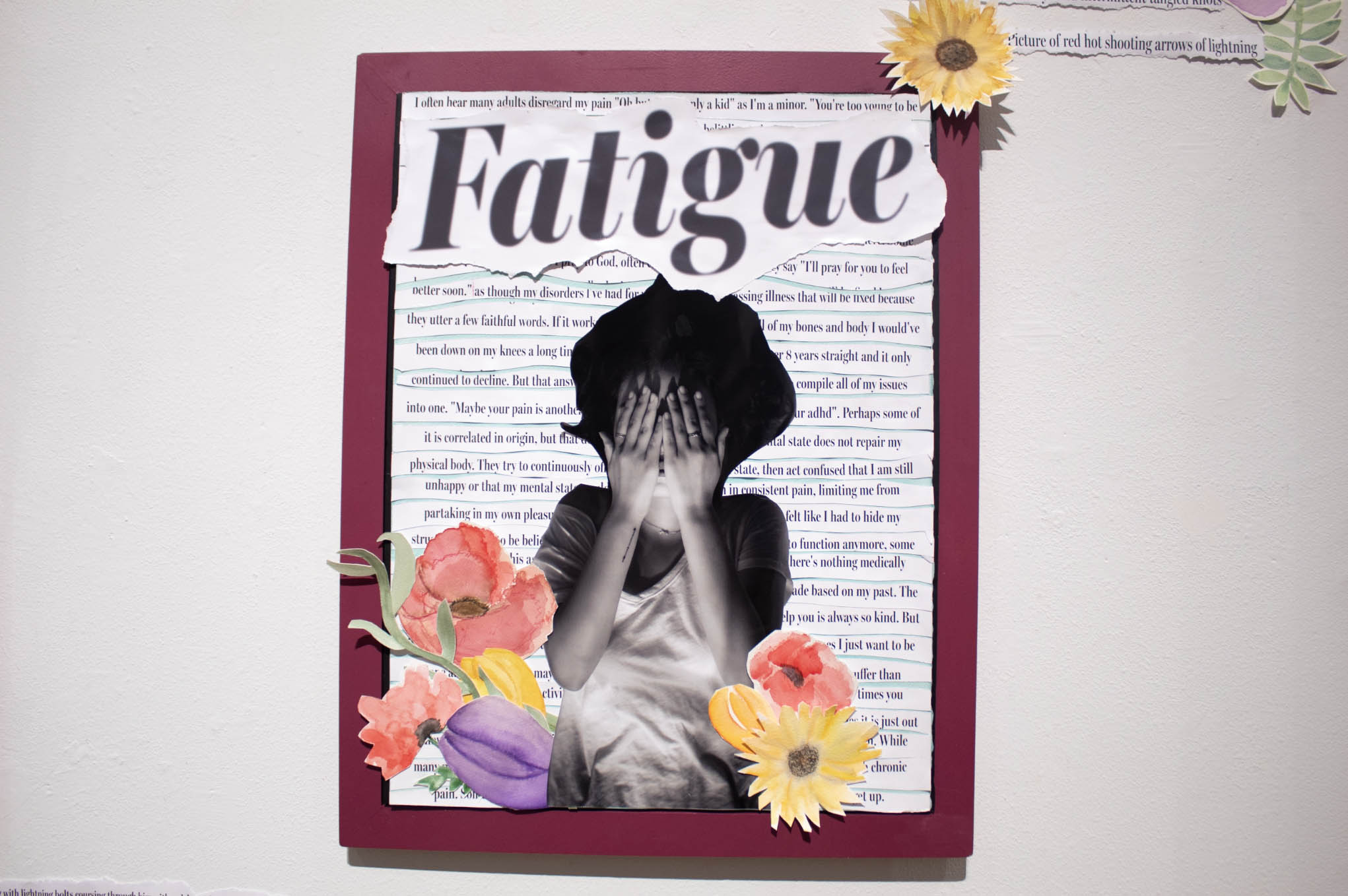 Collage with the word "Fatigue," a black-and-white photo of a person covering their face, and colorful paper flowers on a maroon board.