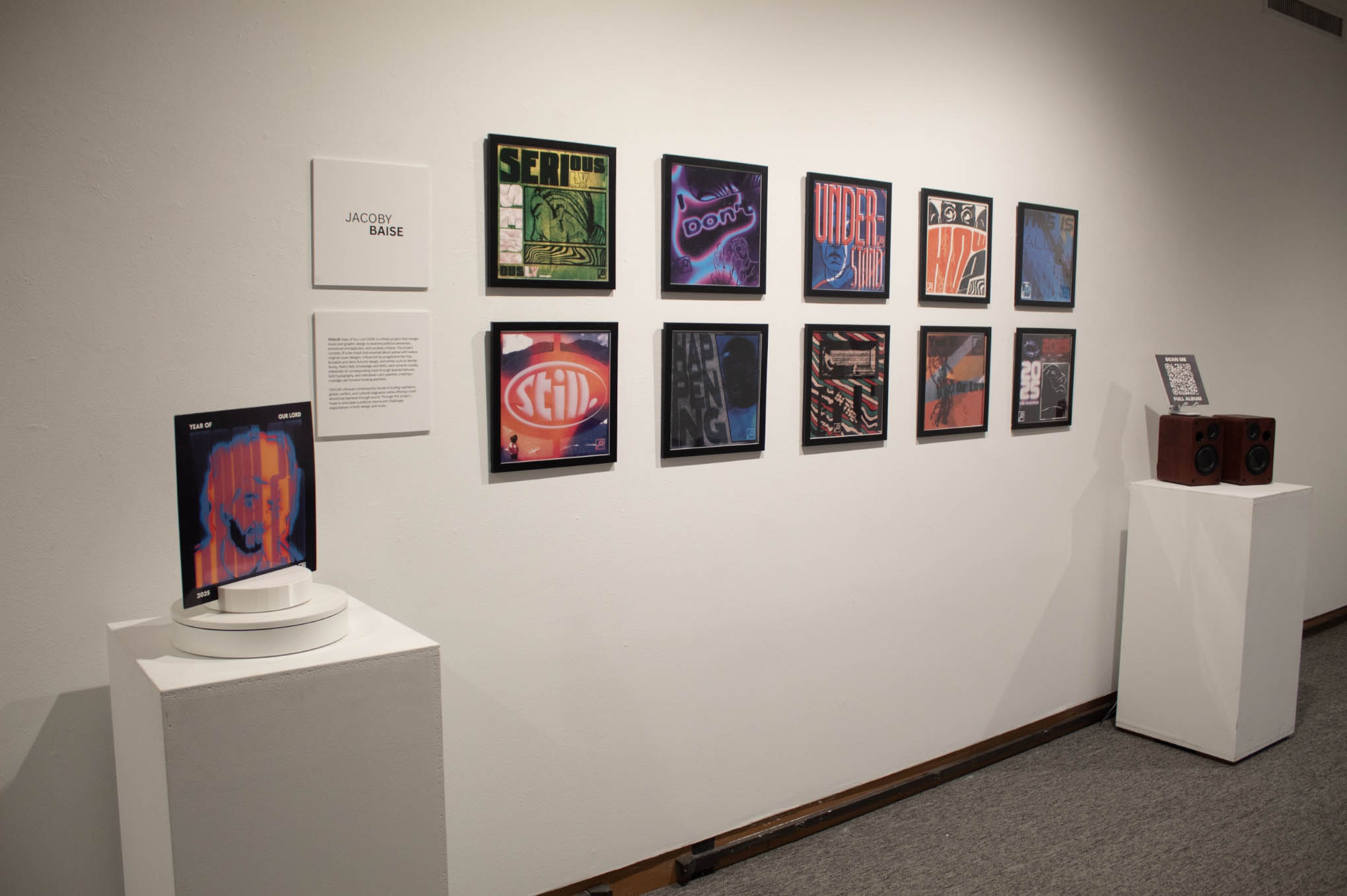 Art gallery exhibit with framed abstract artwork and a pedestal display featuring a colorful portrait.