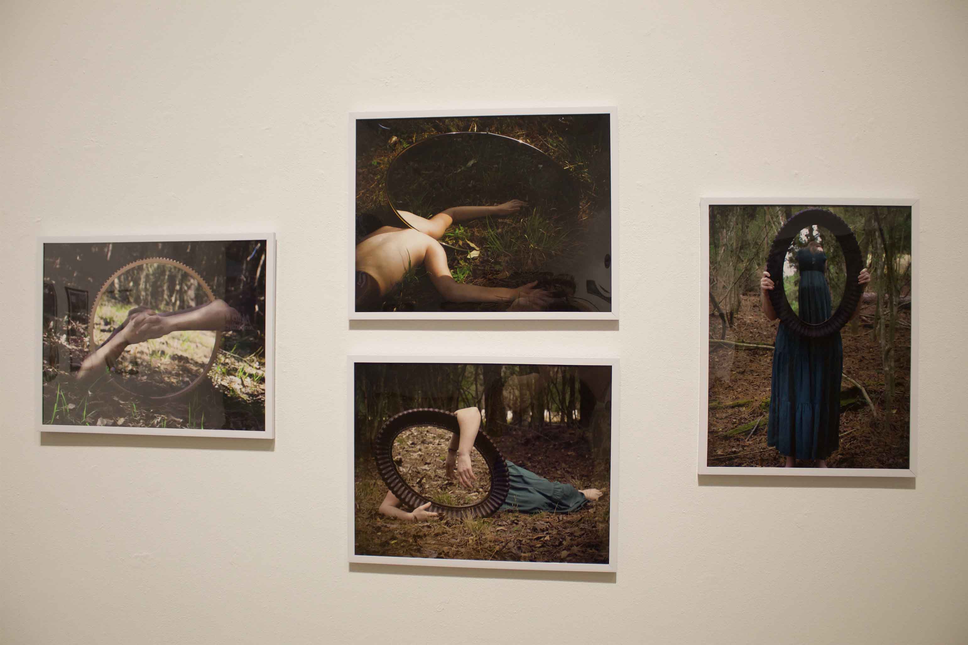 A set of four photographs on a wall, each featuring a circular mirror reflecting natural settings.