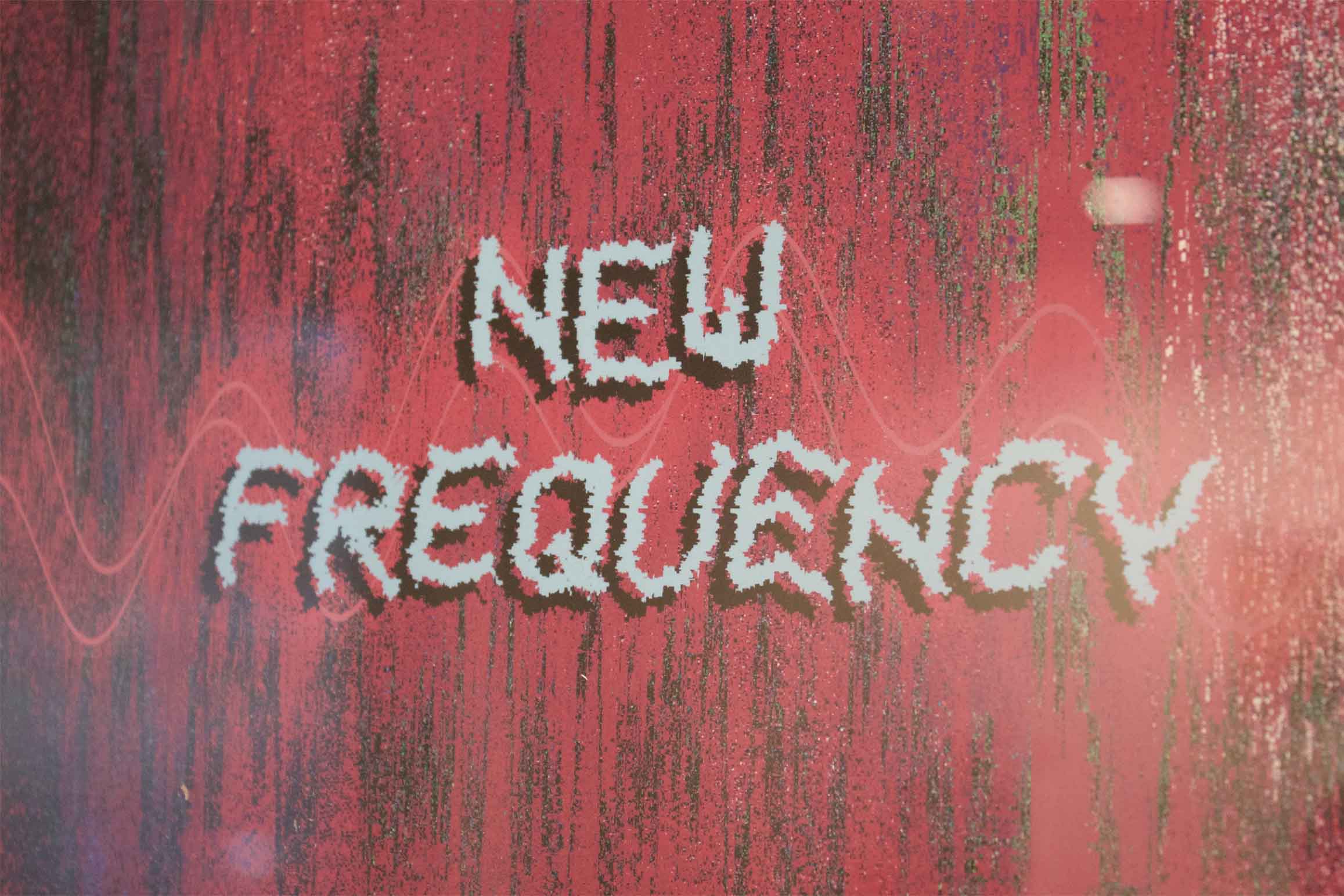 White text "NEW FREQUENCY" on a red, textured background with black streaks and subtle wave patterns.