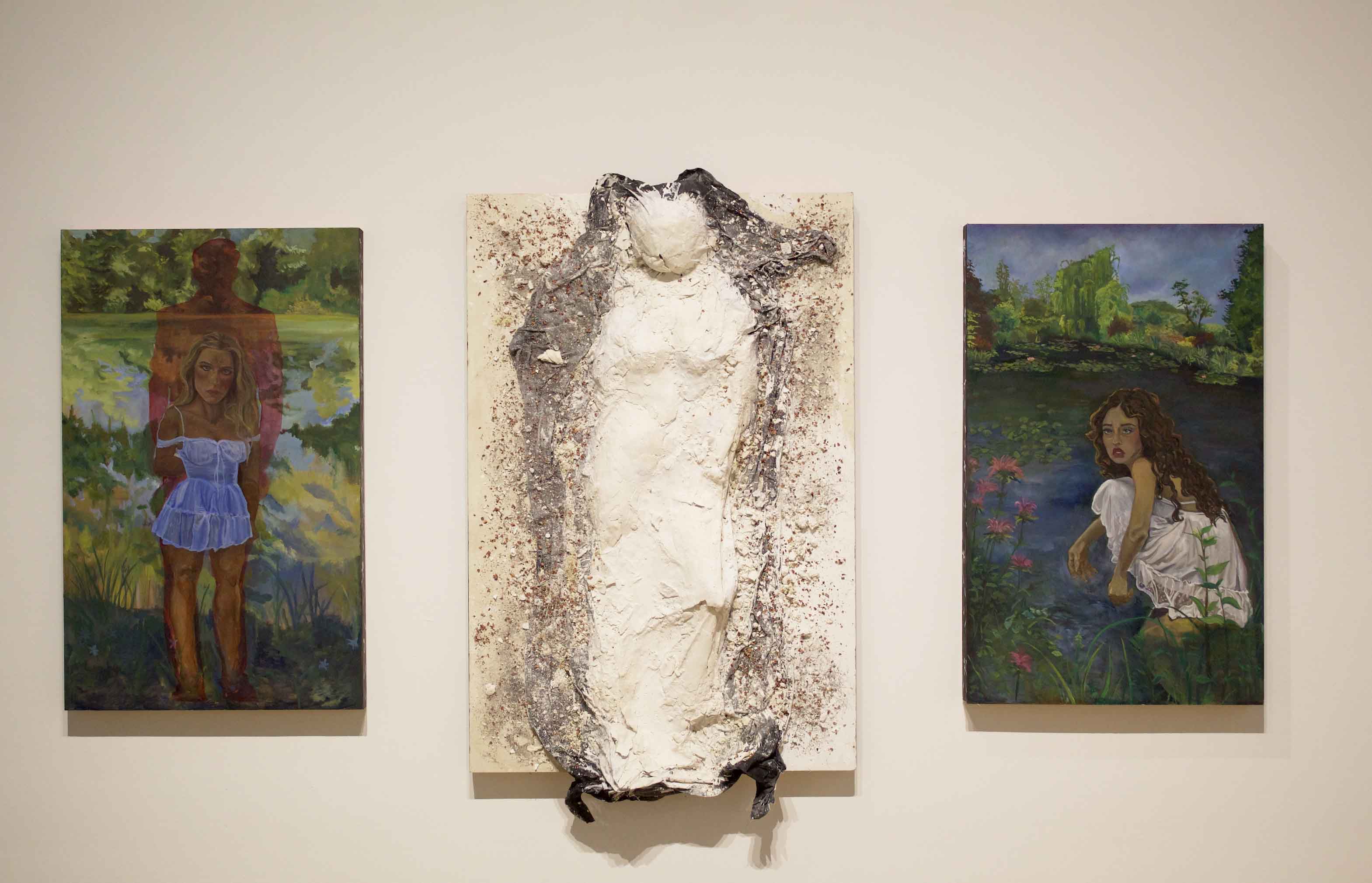 Three artworks on a wall: a painting of a woman in a blue dress, a textured plaster sculpture, and a painting of a woman in water surrounded by nature.
