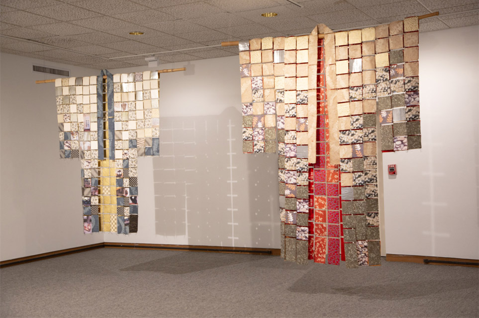 Two hanging textile kimonos made from patchwork squares, one in cream and blue tones, the other in red and gold.