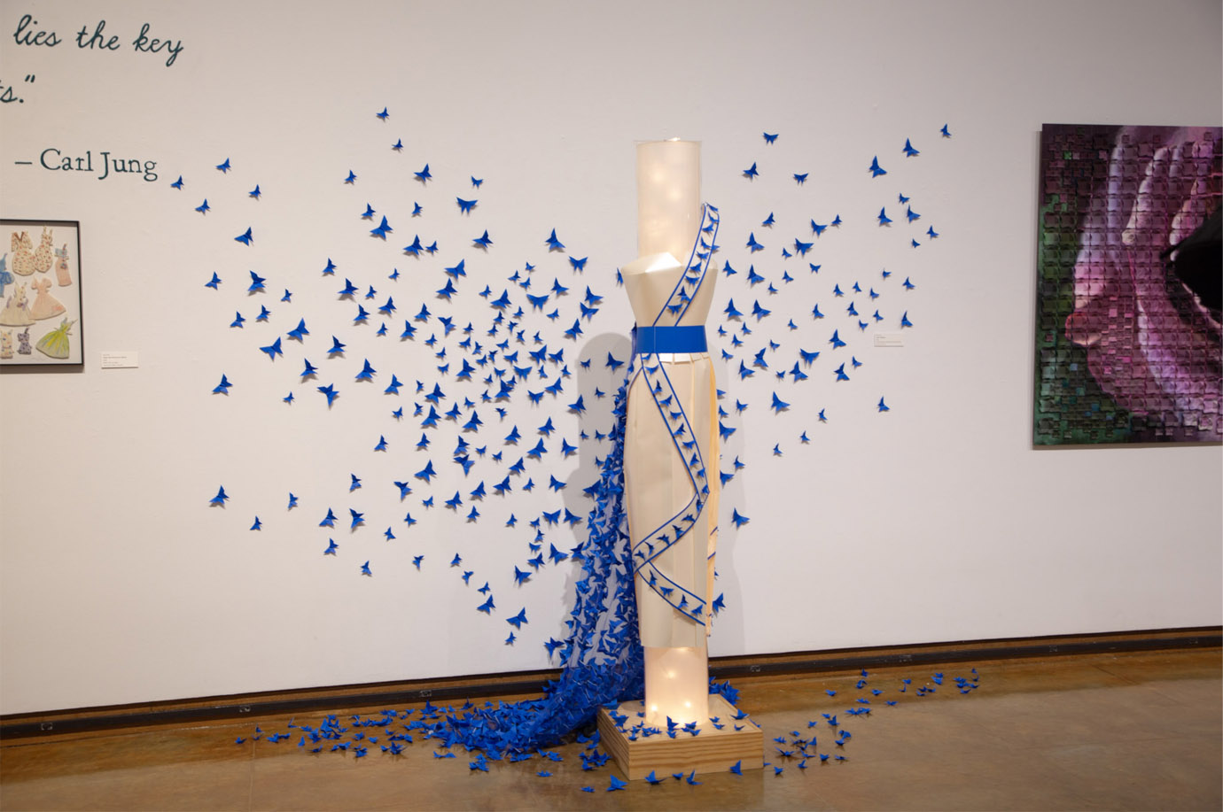 Mannequin with a blue-trimmed dress surrounded by a swarm of blue paper butterflies.