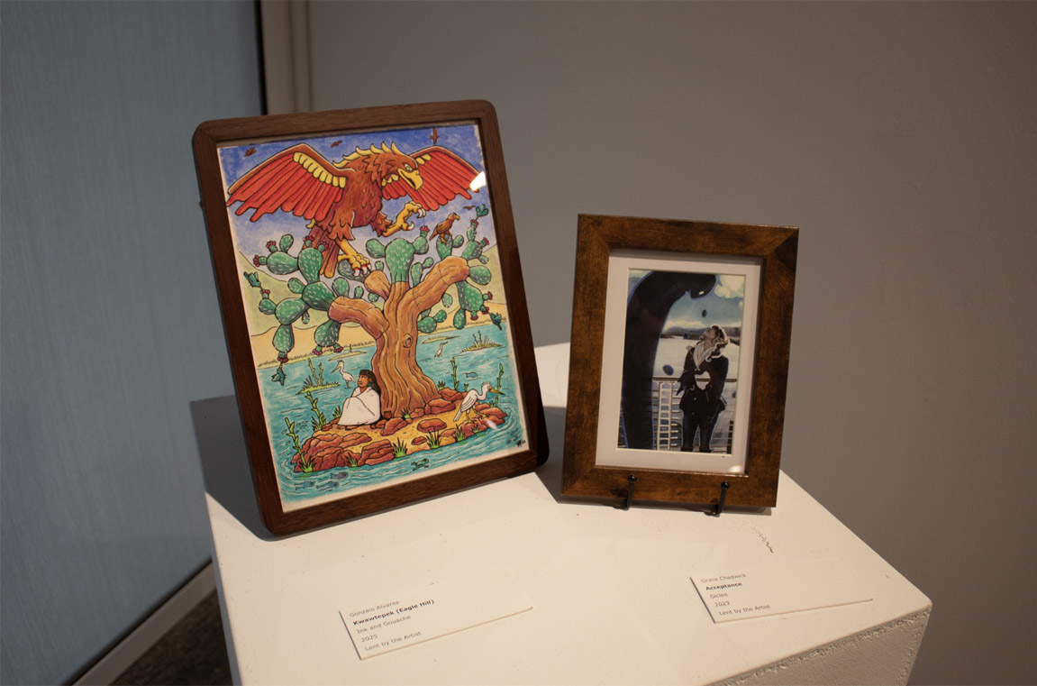 Two artworks on a pedestal: a colorful desert scene with a tree and eagle on the left, and a couple embracing in a surreal landscape on the right.