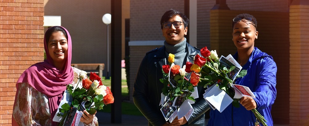 students standing in sunlight with flowers on valentines day