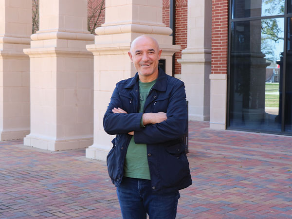 Dr. Agim Kukeli standing outside of the Reaud Honors Building