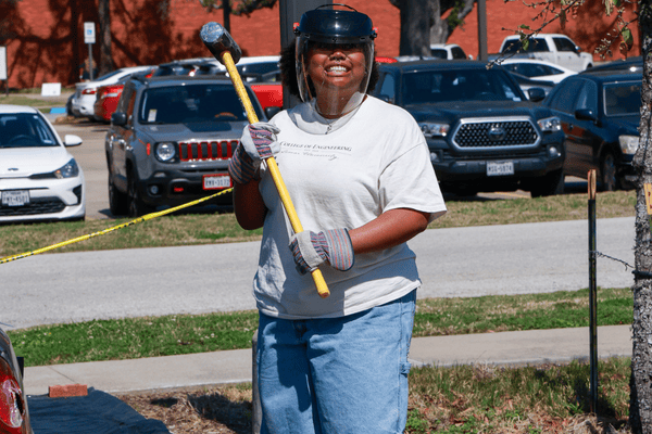 Student Smiling with Hammer in Their Hand at Car Smash Event 