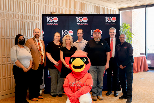 distinguished staff posing with president, provost, and big red mascot
