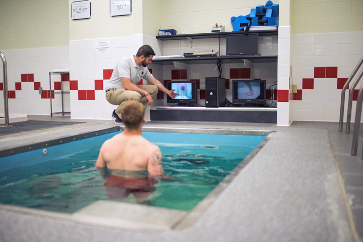 LU assistant athletic trainer, David Kovner, assists Dallas Martin, junior linebacker, in using the underwater treadmill. UP photo by Noah Dawlearn