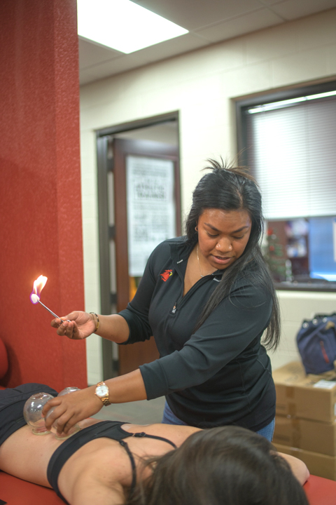 Assistant athletic trainer Emlyn Ngiratmab, practices fire-cupping, a technique used to bring blood to the surface after an injury, can also be used to increase flexibility and revive tired muscles. UP photo by Noah Dawlearn