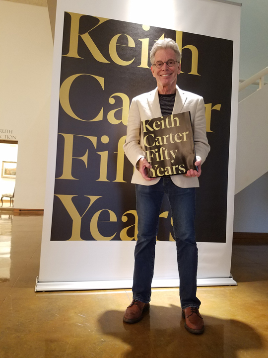 Keith Carter stands with a copy of his retrospective book in the Dishman Art Museum, which is hosting an exhibition of the same name. UP photo by Sierra Kondos