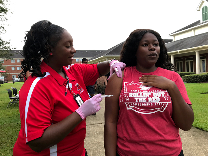 Dalesia Harris, Beaumont senior, right, gets ready for her flu shot from Albertine Ambers, nursing aide, Oct. 15, on the Dining Hall front lawn. UP photo by Delicia Rocha