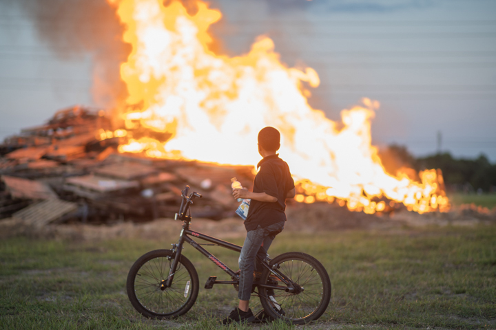 A student on a bike watches the bonfire burn at Lamar University's Homecoming Pep Rally and Bonfire, Sept. 27. UP photo by Noah Dawlearn