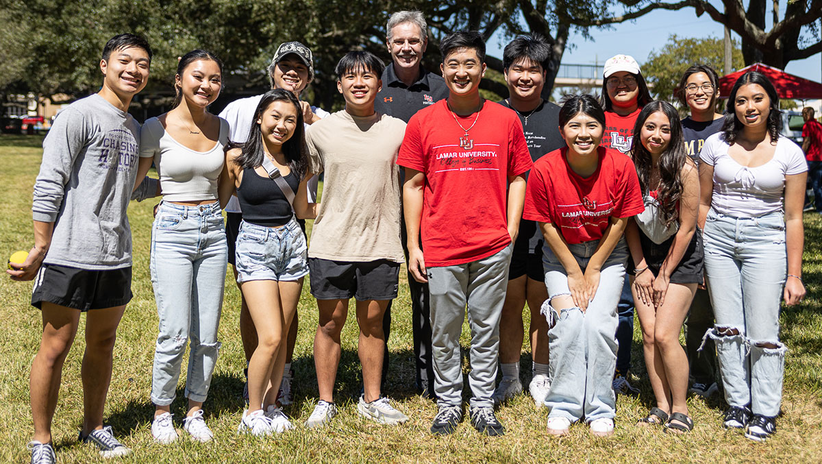 The Asian Business Student Association poses for a picture with President Jaime Taylor during the Homecoming tailgate at the field by the Plummer Building, Oct. 1. UP photo by Brian Quijada.