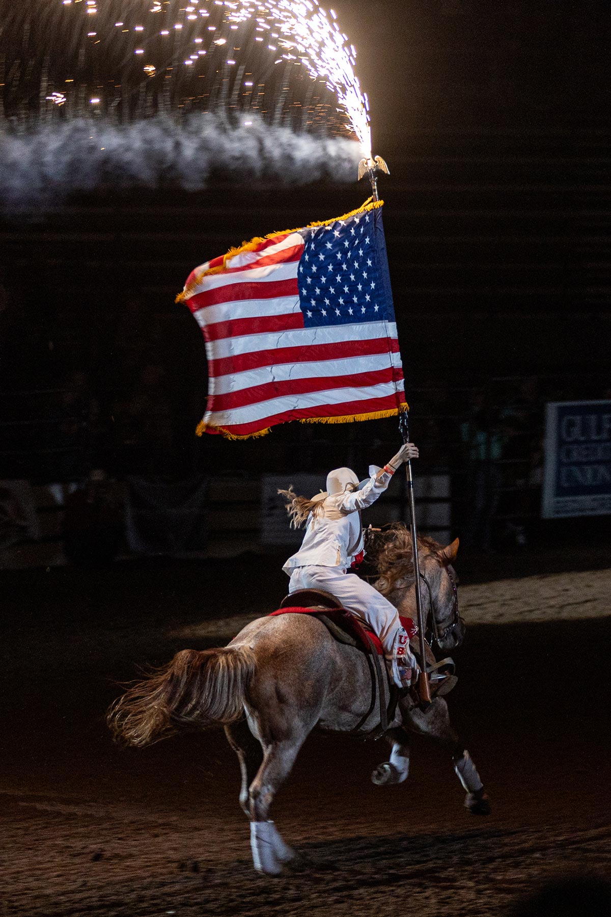 A woman rides off on a horse holding a U.S. flag with sparkles before the South Texas State Fair Rodeo, Beaumont, Texas, March 23. UP photo by Brian Quijada.