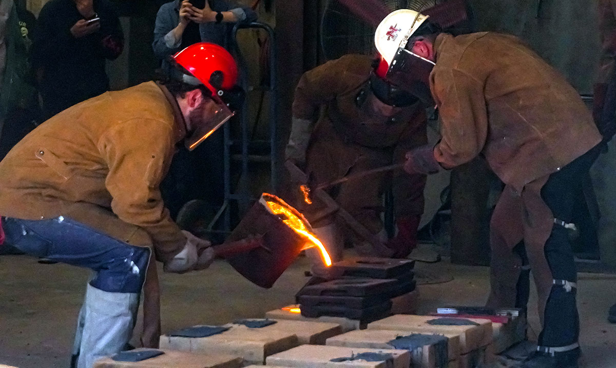 Art students pours the molten iron into the sand mold, March 22, at the art foundry. UP photo by Carlos Viloria.